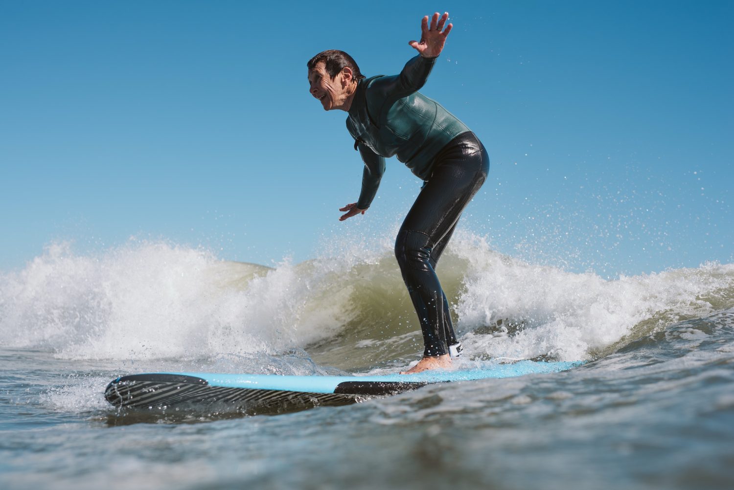 An adult student riding a wave with a huge smile