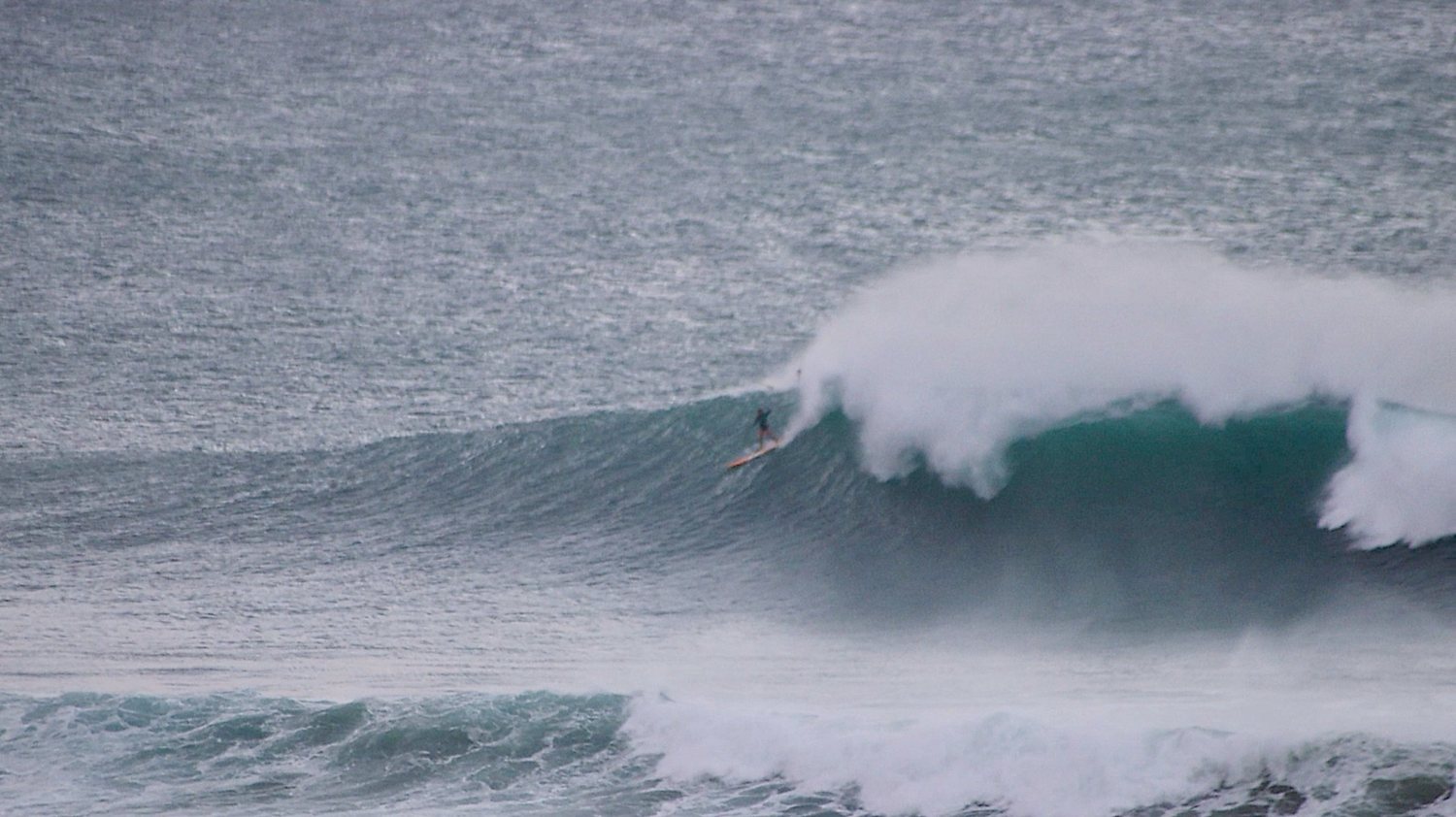 Bri Young dropping into a big grey winter wave