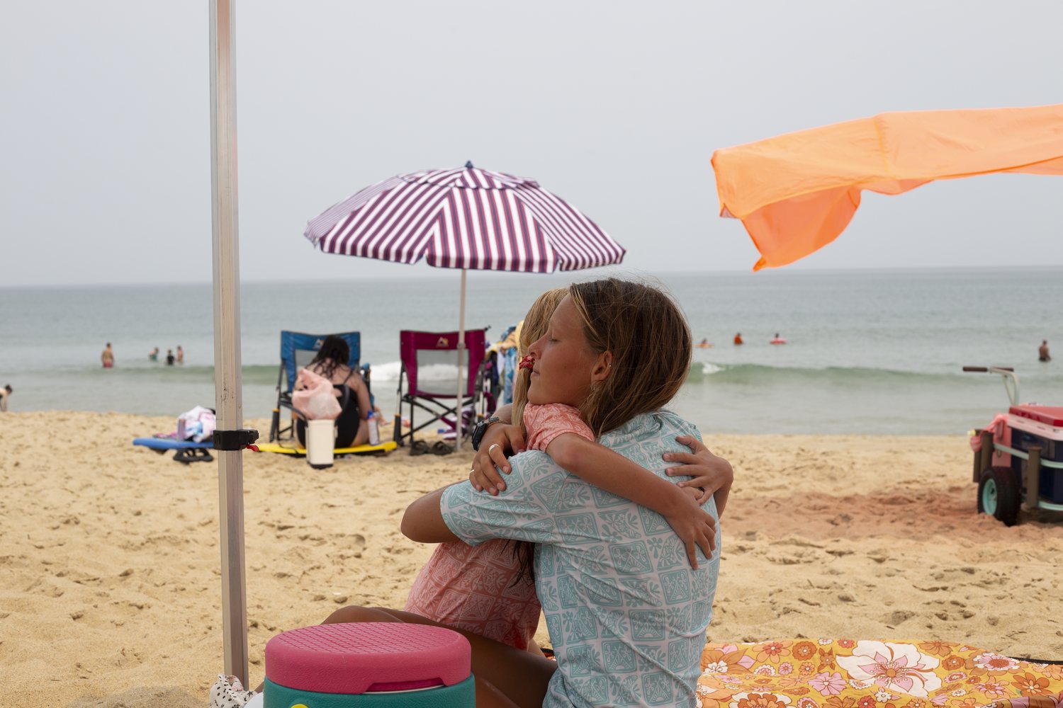 An instructor and a camper sharing a big hug on the beach