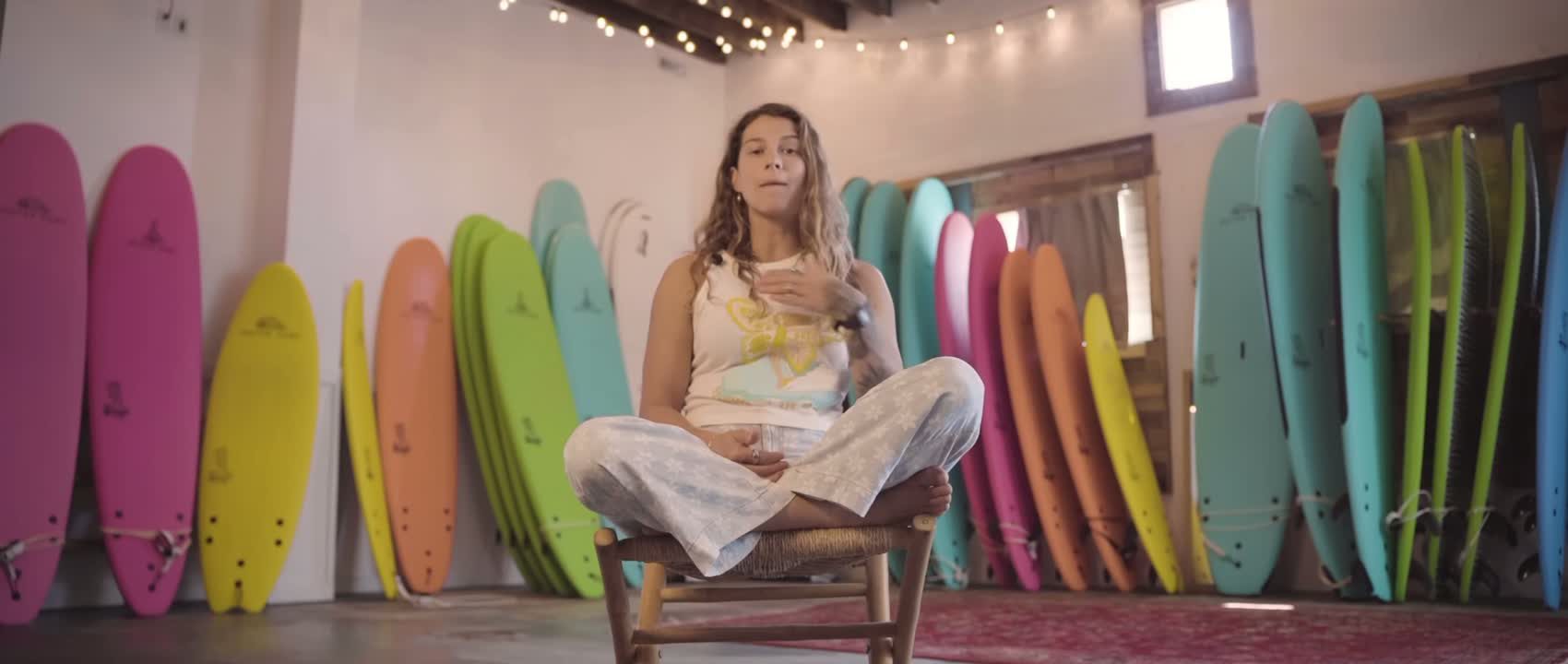 Bri Young sitting among a rainbow of soft-top surfboards