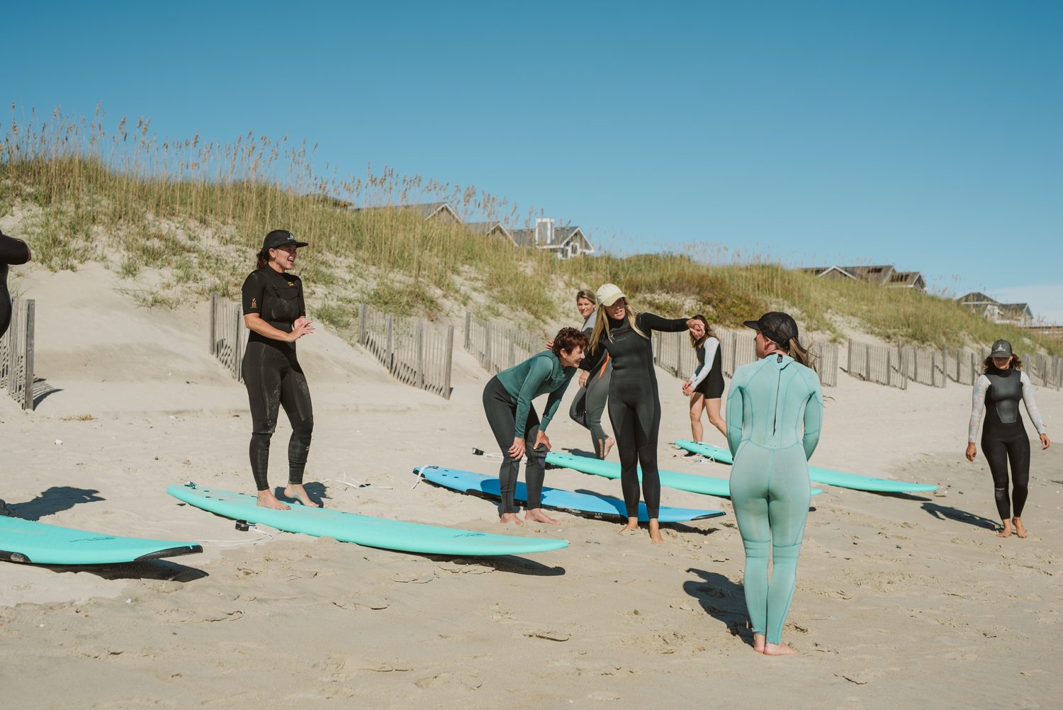 An Outer Surf instructor coaching a group lesson on the sand by the dunes